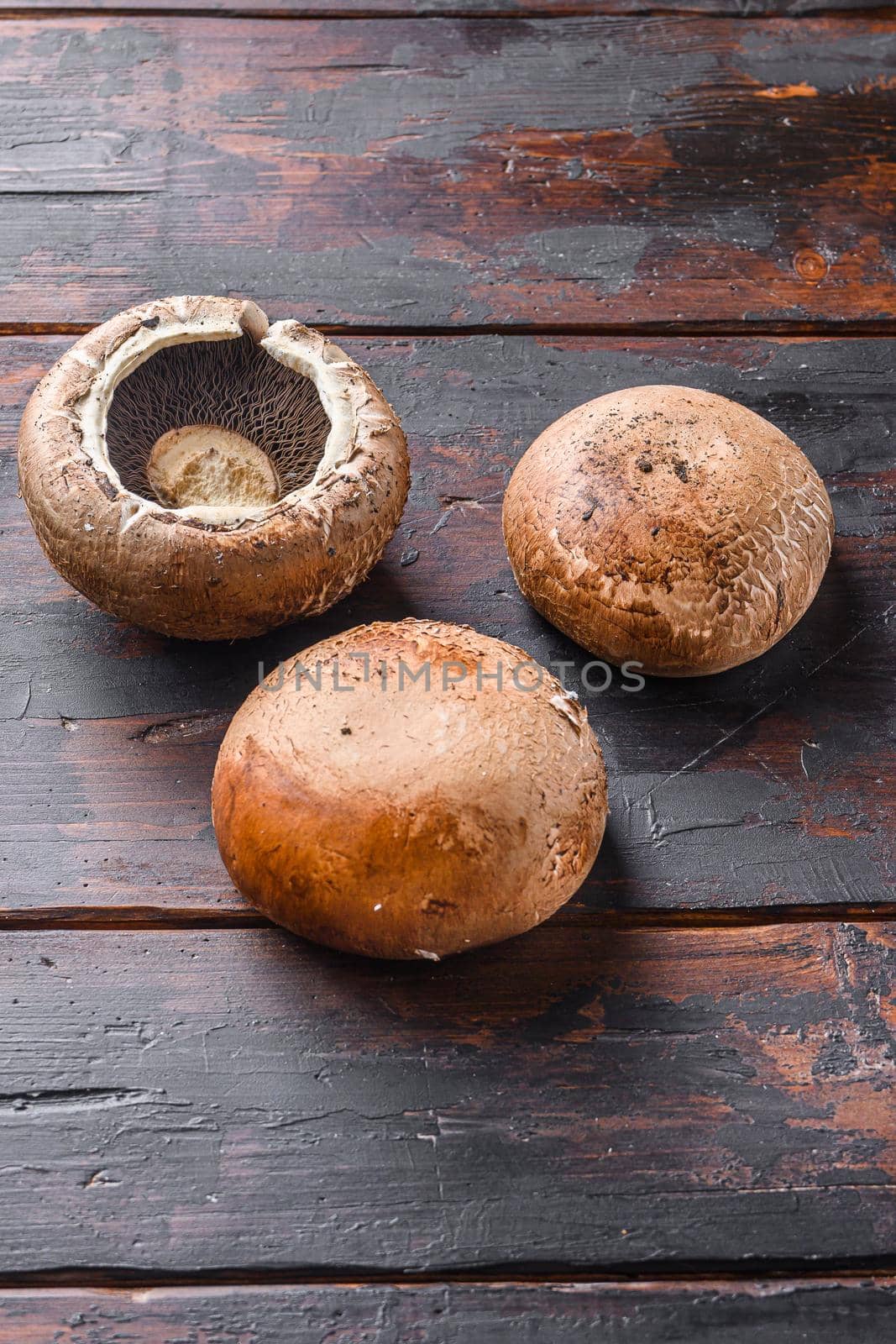 Raw portobello mushrooms set on dark old wood table side view