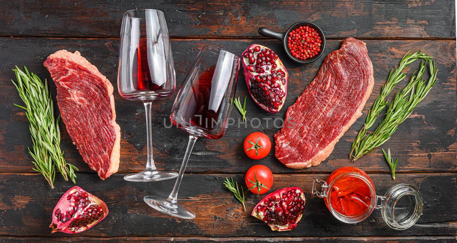 Picanha Center-Cut Steak with glasses of red wine, herbs and pomegranate top view old dark wooden background. Big size