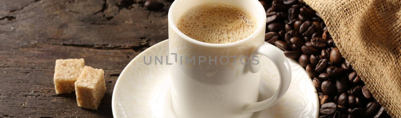 cup of coffee espresso in white porcelain cup with roasted coffee beans on old wood background with canvas bag