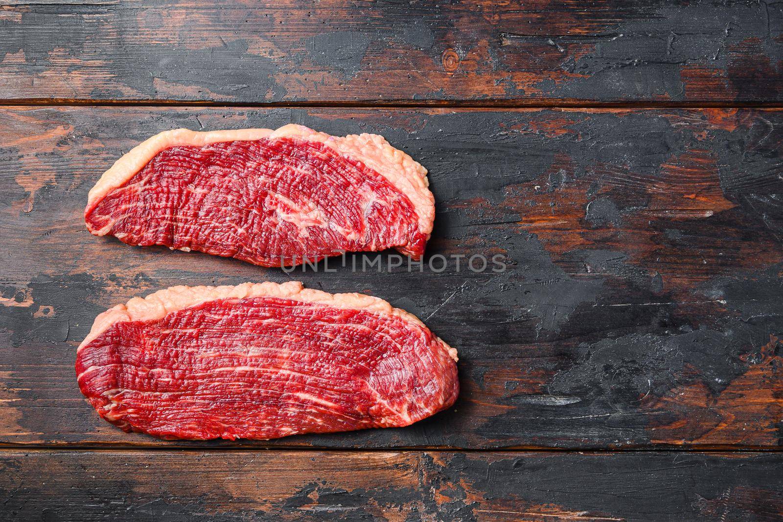 Pair of organic picanha beef meat steaks, over dark old wooden background, top view with space for text