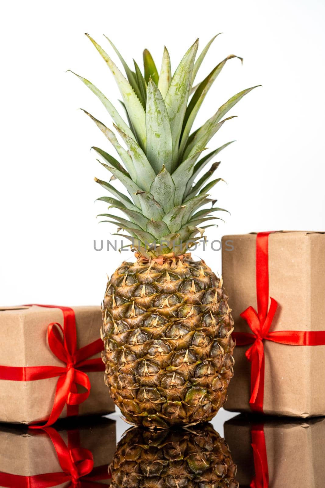 Fresh pineapple and gift boxes on black glass table on white background by galinasharapova