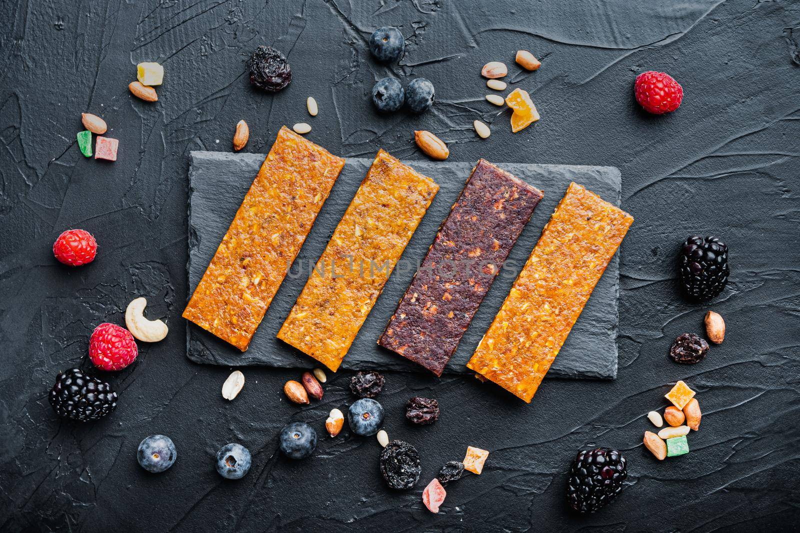 Fruit berry nut energy bars, healthy snack, flat lay, on black background
