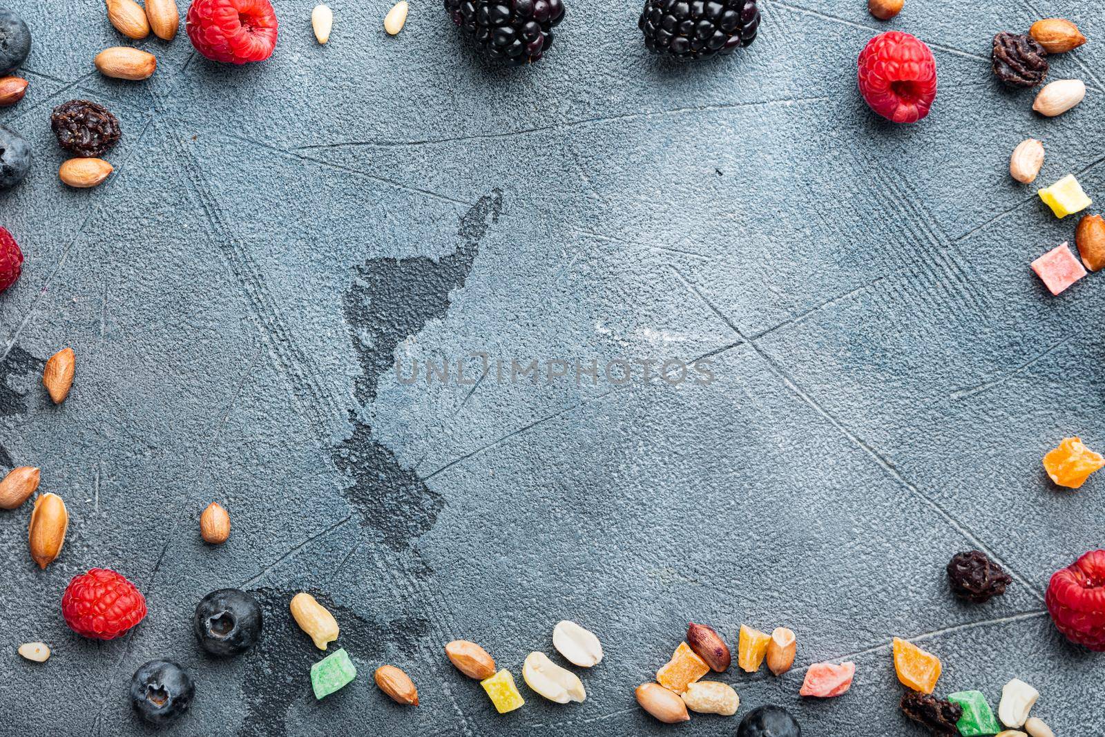 Frame made of mixed dried and raw ripe berry and fruit with nuts, flat lay with space for text, on grey background
