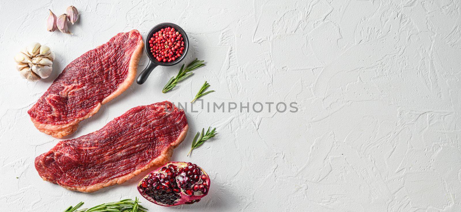 Couple picanha beef steak with rosemary and pomegranate top view over white textured background . Big size space for text. by Ilianesolenyi