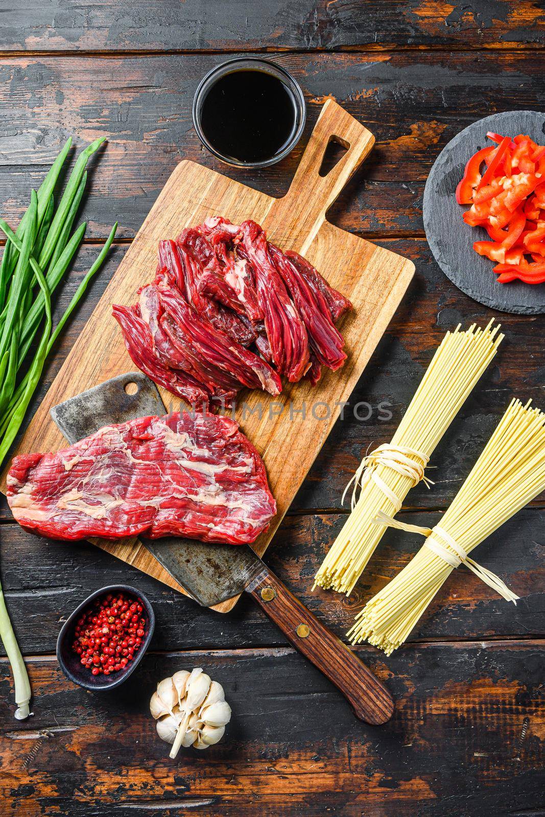 Chinese noodles with vegetables, . Machete steak and butcher cleaver over wooden background. Top view