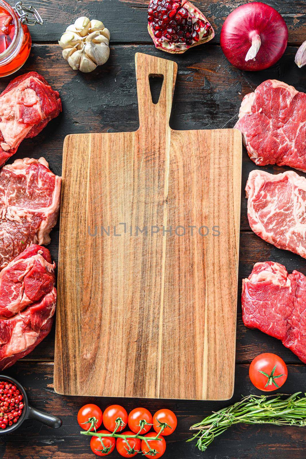 Meat beef steaks frame concept, with different steak cuts andempty chopping board in frame on dark old wooden table top view