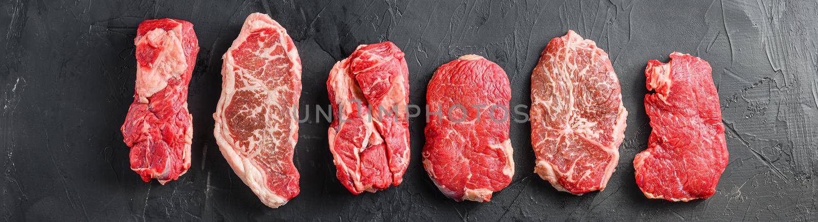 Variety of raw alternative steaks picanha, ramp and chuck eye roll and top blade over black background top view. Big size. Banner view. by Ilianesolenyi