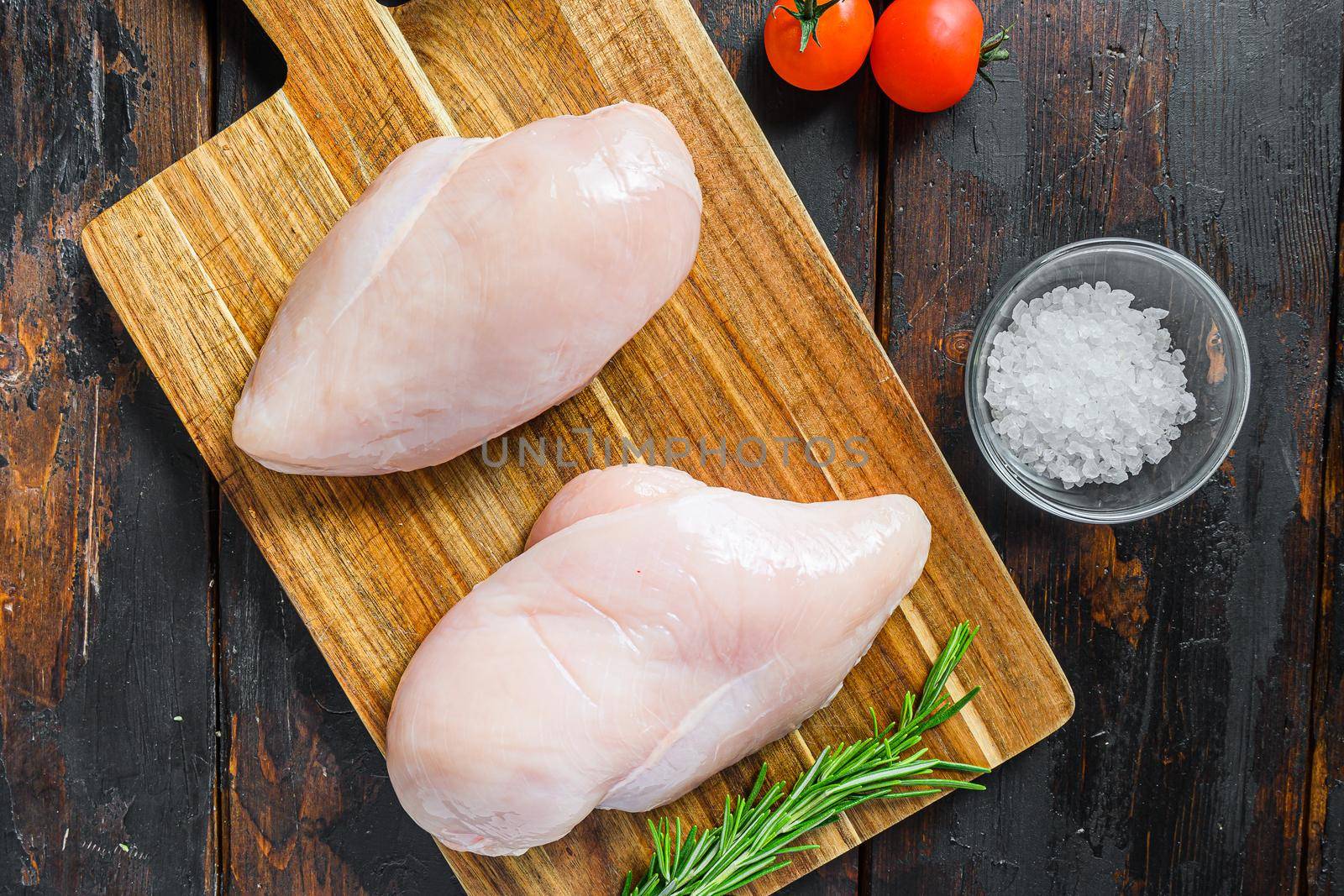 Raw meat, ready for grill or barbeque chicken breast filet, with herbs and spices on dark rusty wooden background, top view close up.