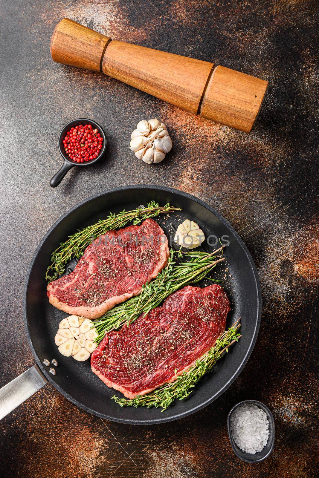 Picanha organic beef steaks ready for grill on pan with herbs and garlic. Over old dark metall background, top view