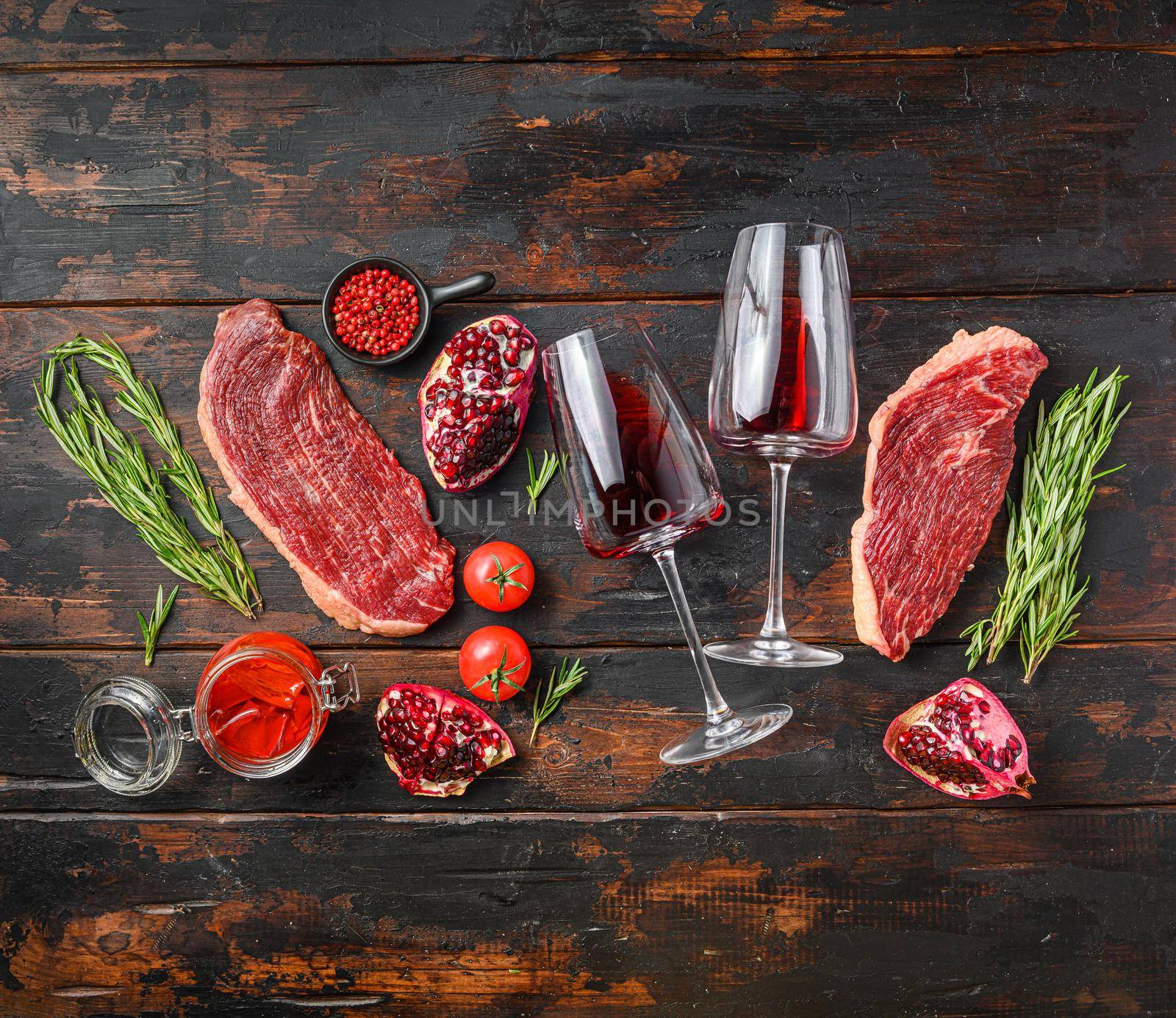 Picanha Center-Cut Steak with glasses of red wine, herbs and pomegranate top view over old dark wooden table. Big size