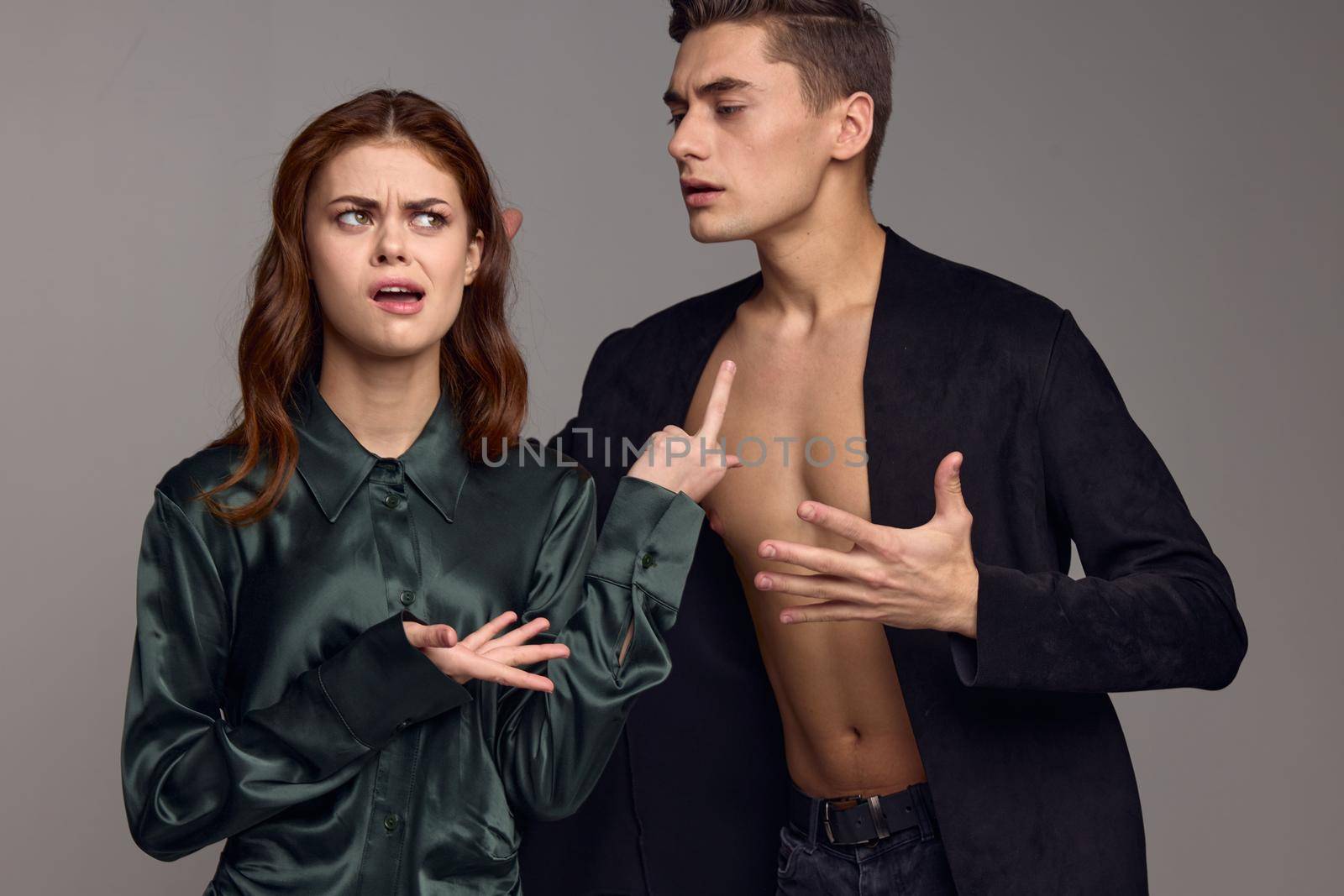 Conflict situation young people in suits on a gray background gestures with their hands problems in the family. High quality photo