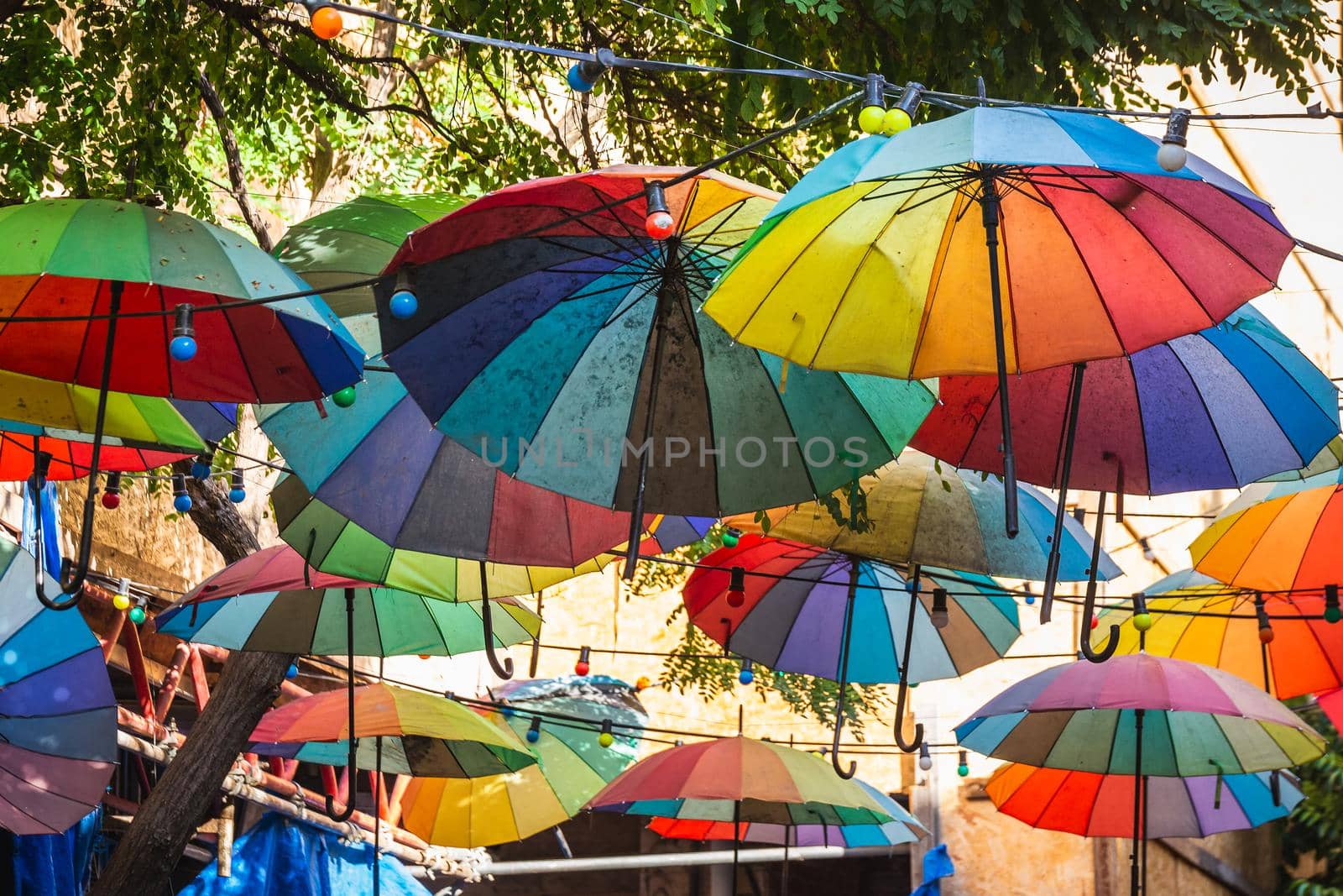 Multicolored umbrellas hang overhead in the street near Galata Tower.