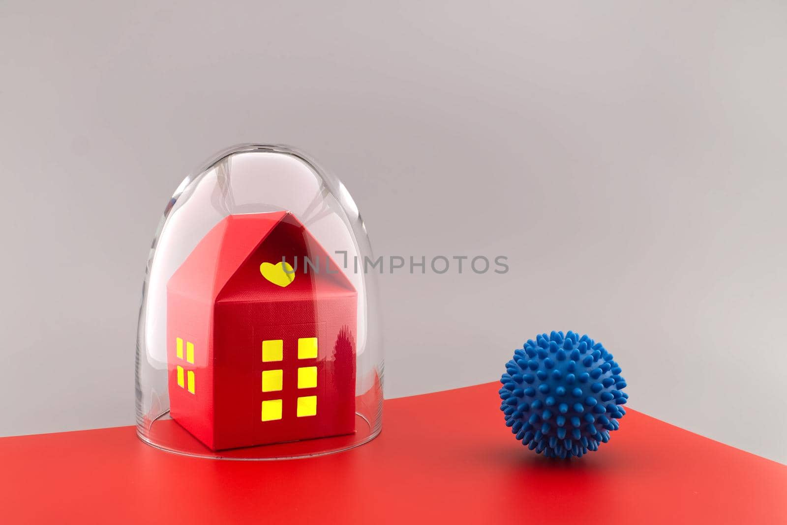 Red building with lights in the windows under protective shield as a concept of covid pandemic and self-isolation, with the ball of coronavirus outside the glass dome