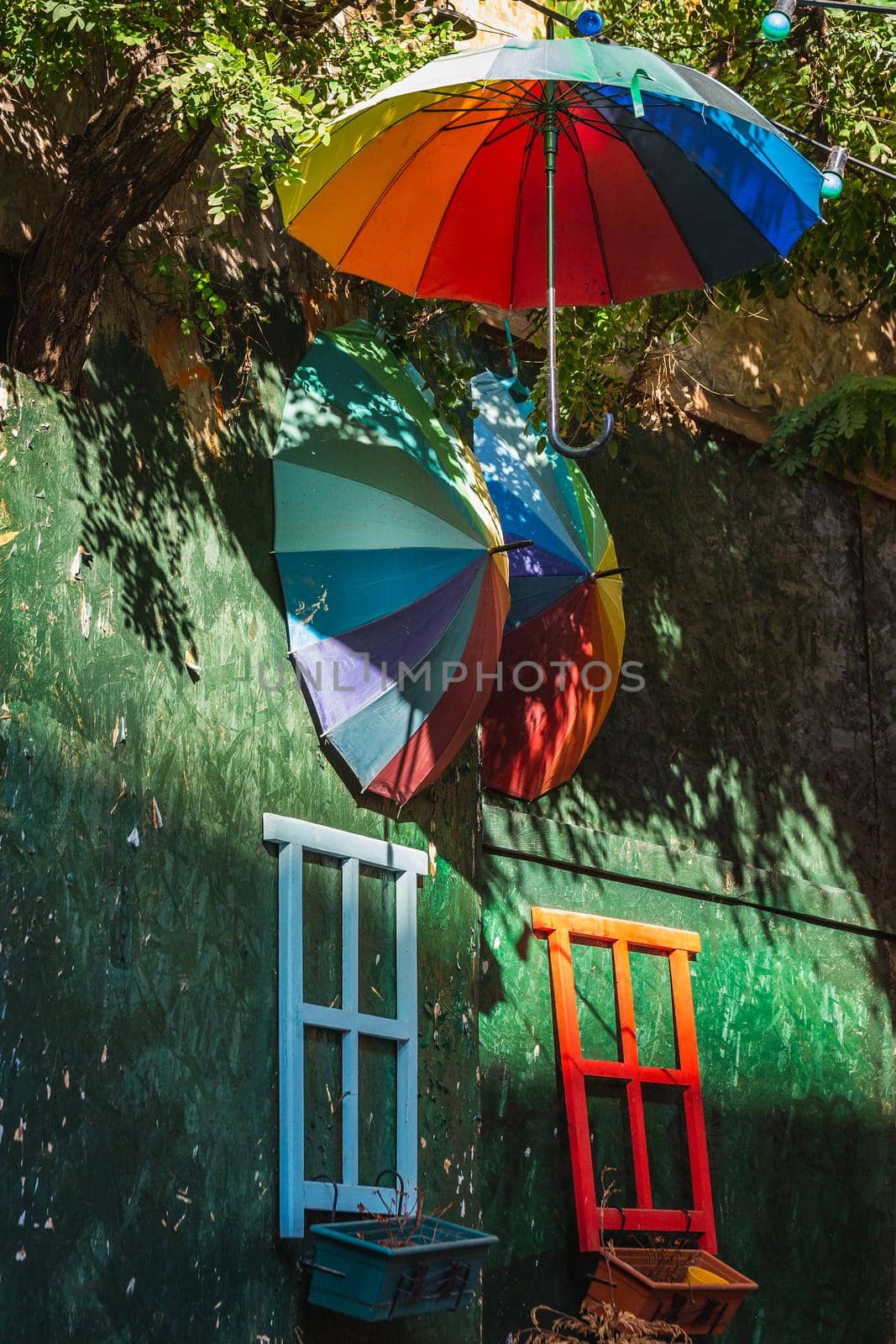 Multicolored umbrellas hang overhead in the street near Galata Tower.