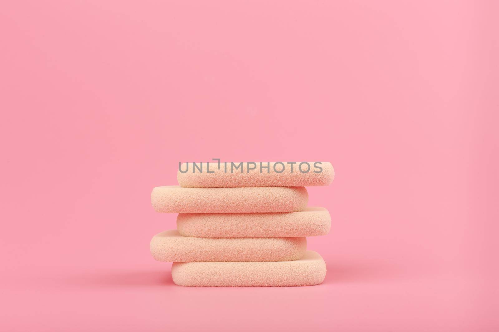 Close up of stack of beige make up sponges on pink background with copy space by Senorina_Irina