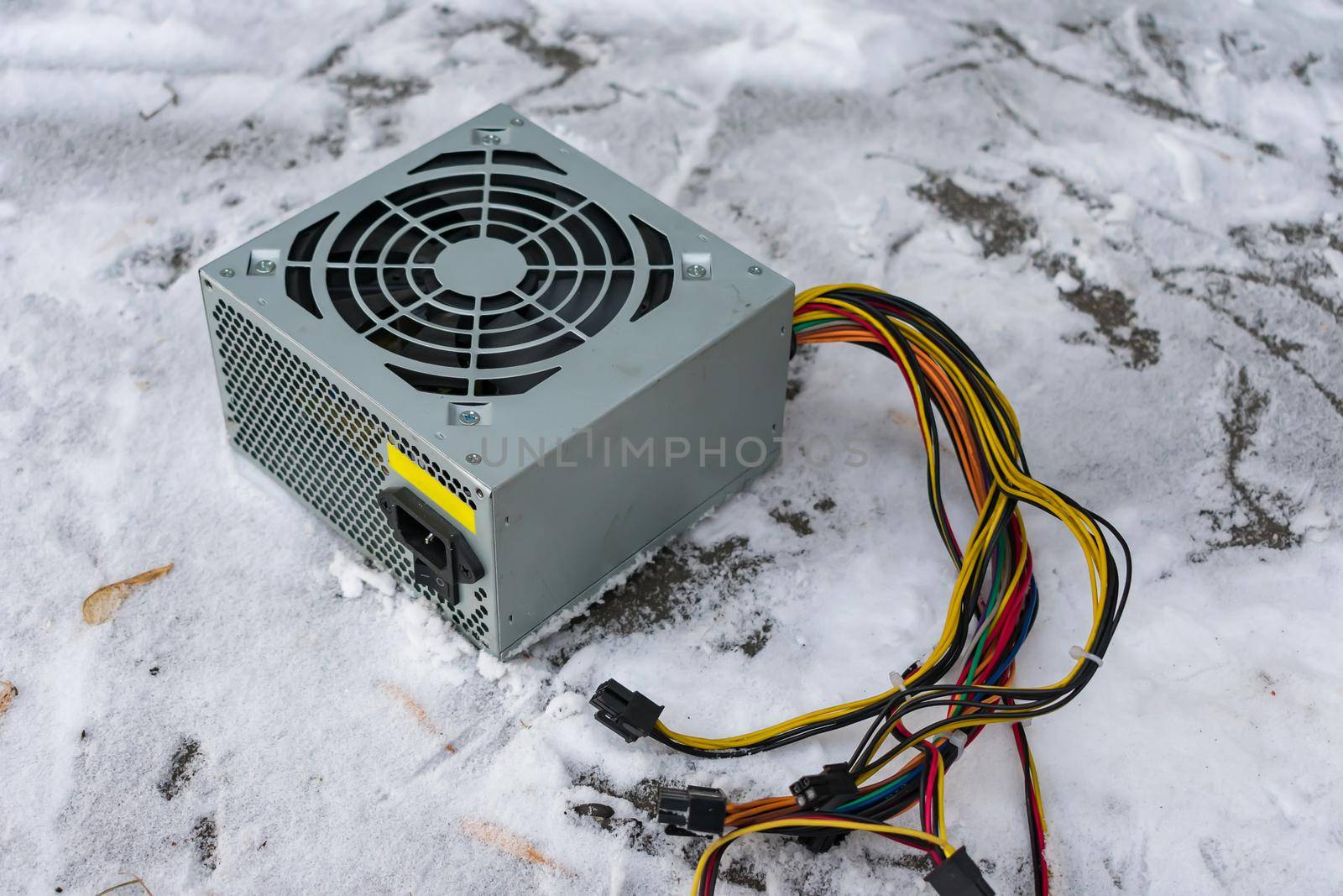 An old computer power supply discarded in the snow in winter