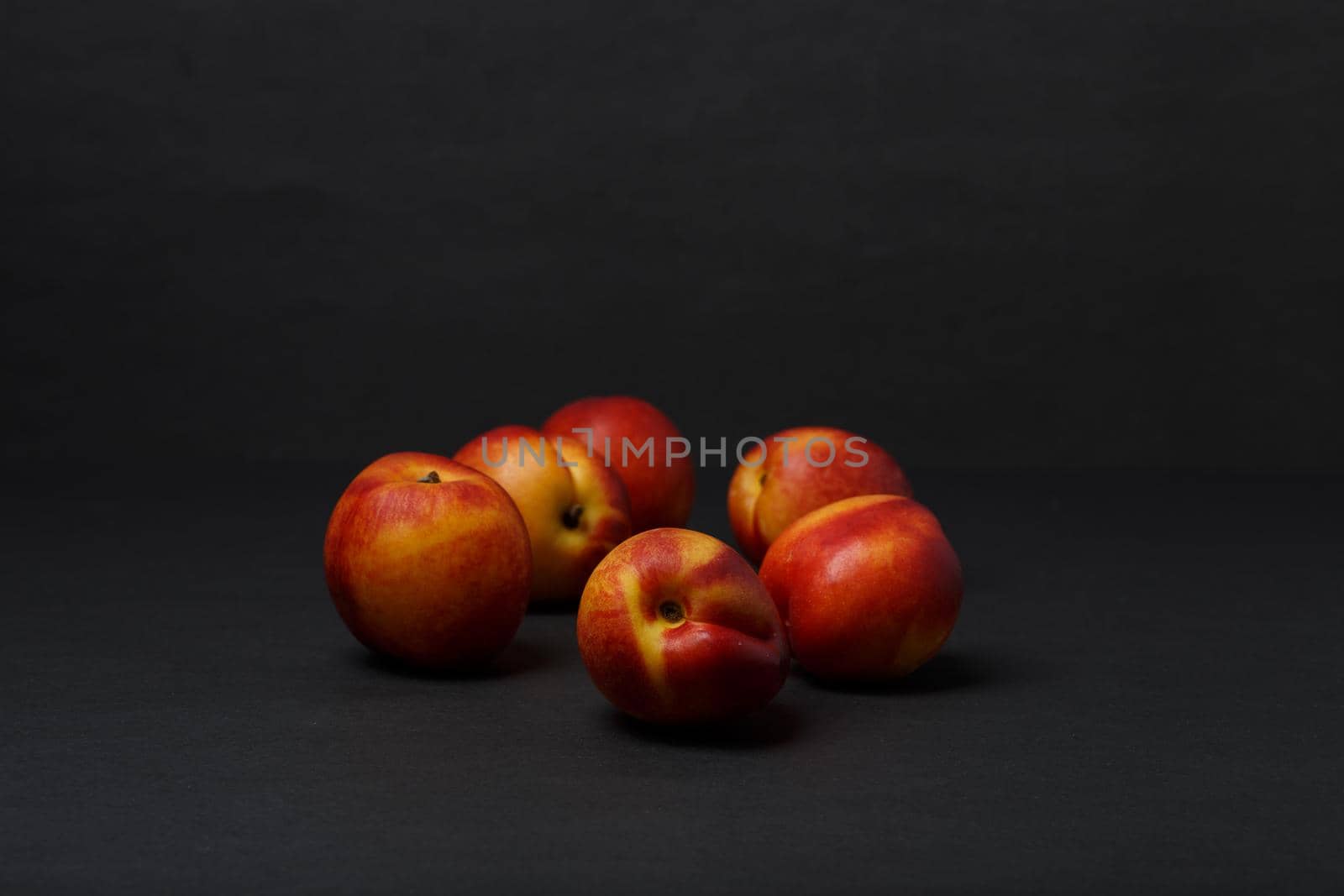 Bunch of nectarines on black table against black background with copy space by Senorina_Irina