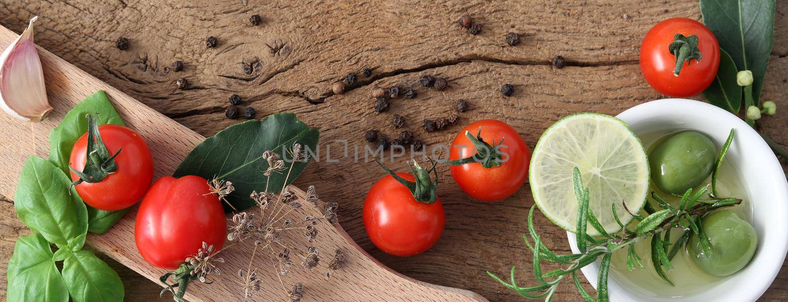Italian Mediterranean cuisine with different vegetables, tomatoes, olive oil, spice, garlic on old wooden background. Fresh ingredients for pizza, pasta. Top view, place for text
