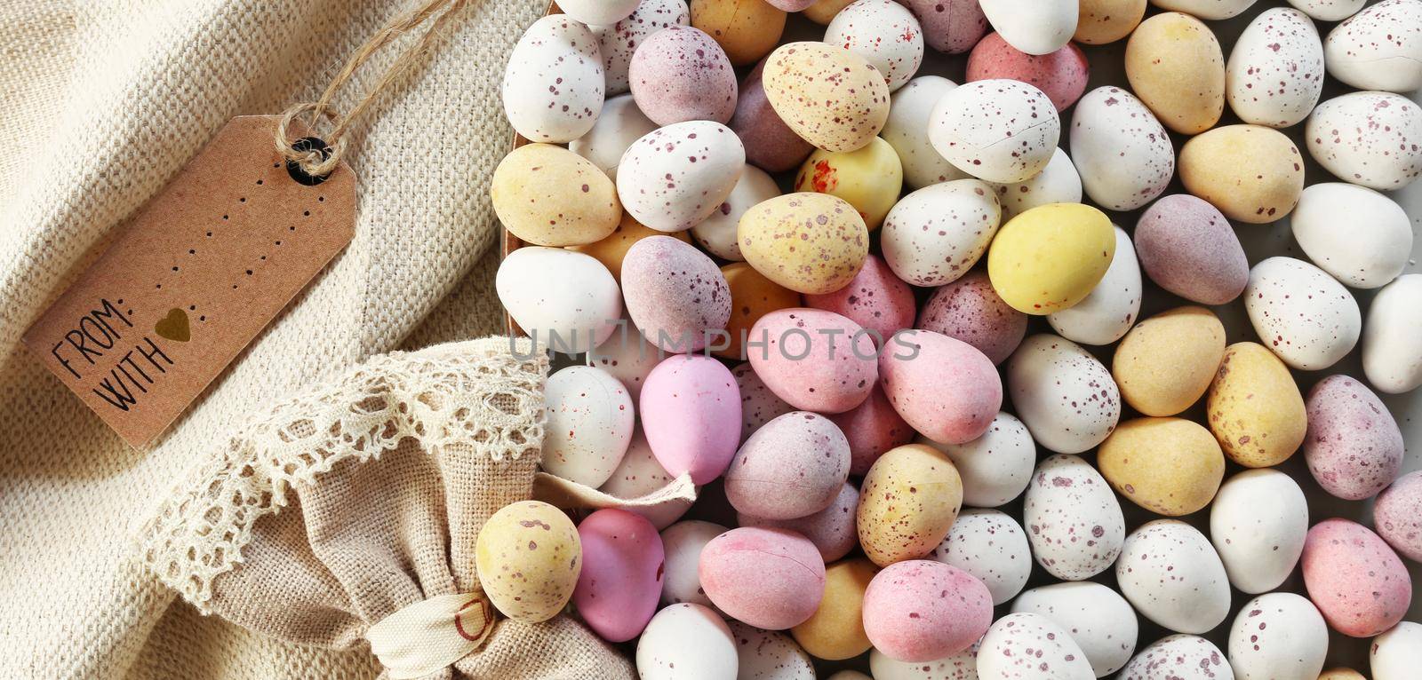 Easter eggs background with colourful eggs with gift tag. Sun light over Easter eggs