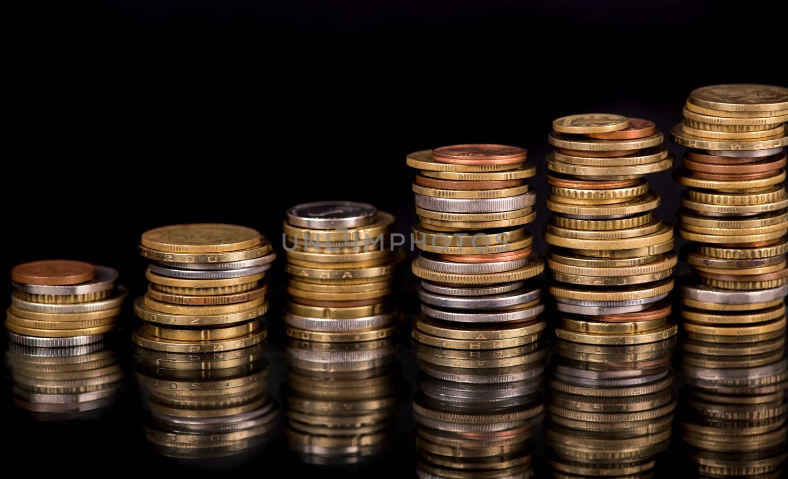 Stacks cf different country coins on black background.