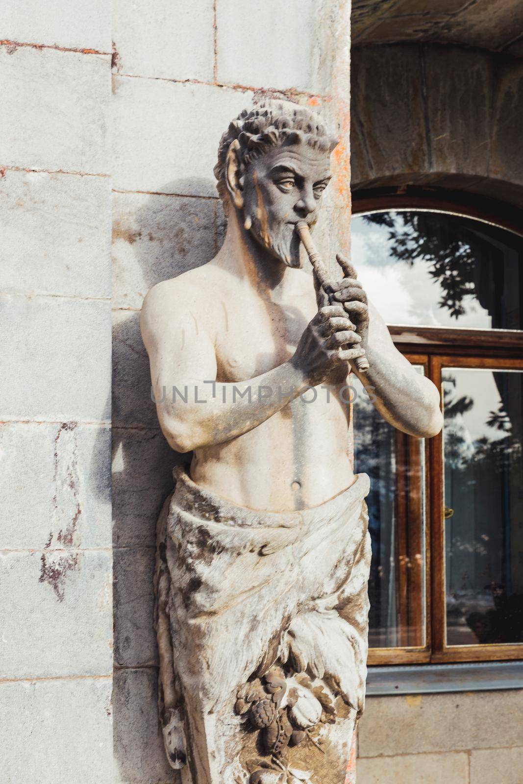 ALUPKA, CRIMEA - February 10, 2015. Statue of Satyr playing the pipe in front of Massandra Palace. Chateauesque villa of Emperor Alexander III of Russia.
