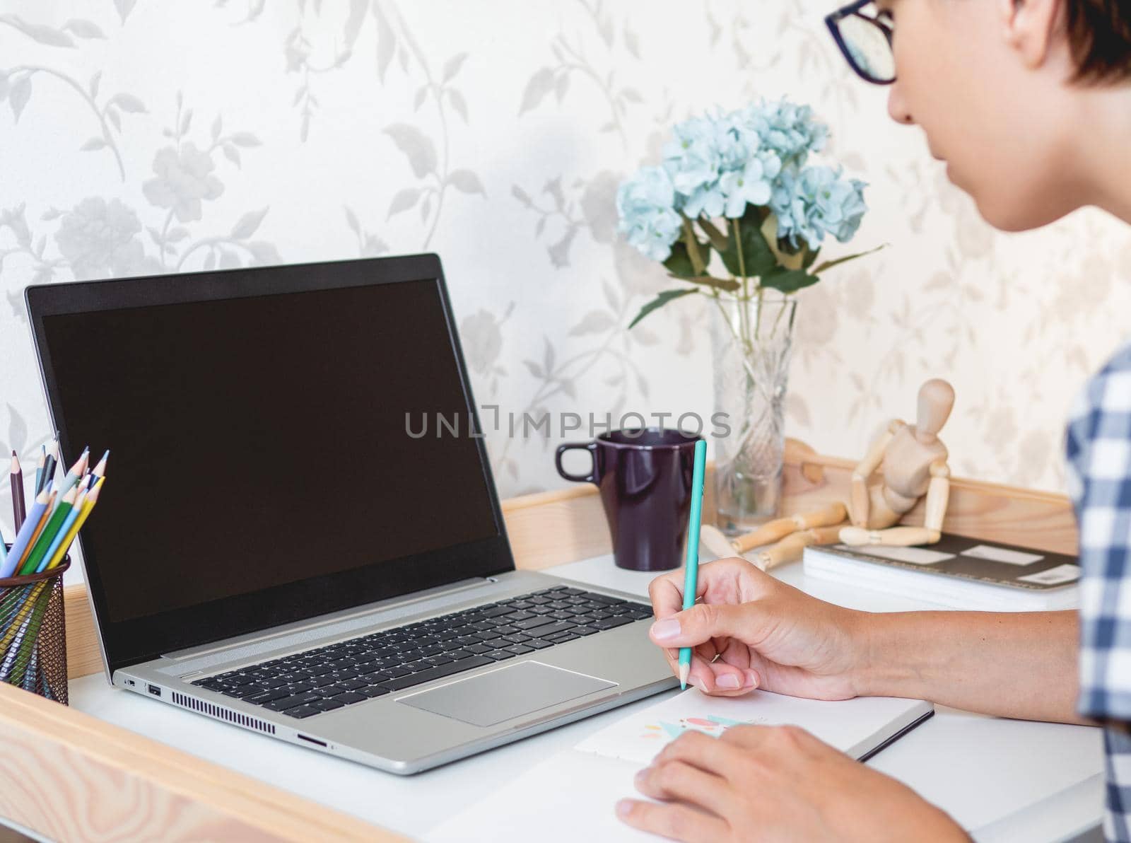Designer or artist at work. Workplace interior - laptop, book, wooden artist's dummy, coloring pencils. by aksenovko