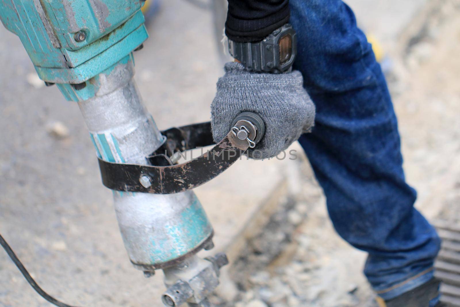 Male workers use electric concrete breaker for digging and drilling concrete repairing driveway surface with jackhammer at the local city road, during sidewalk, work construction site.