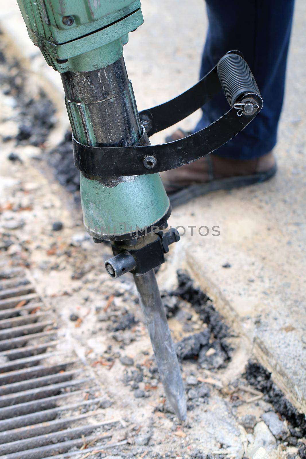 Male workers use electric concrete breaker for digging and drilling concrete repairing driveway surface with jackhammer at the local city road, during sidewalk, work construction site.