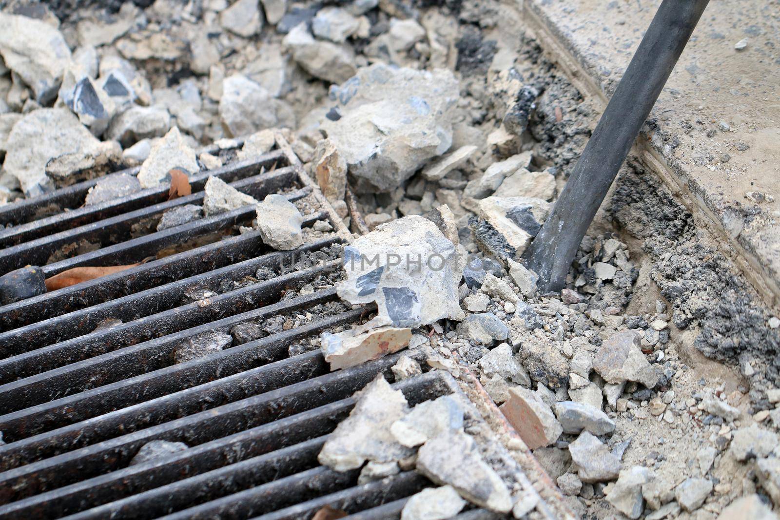 Male workers use electric concrete breaker for digging and drilling concrete repairing driveway surface with jackhammer at the local city road, during sidewalk, work construction site. by NarinNonthamand