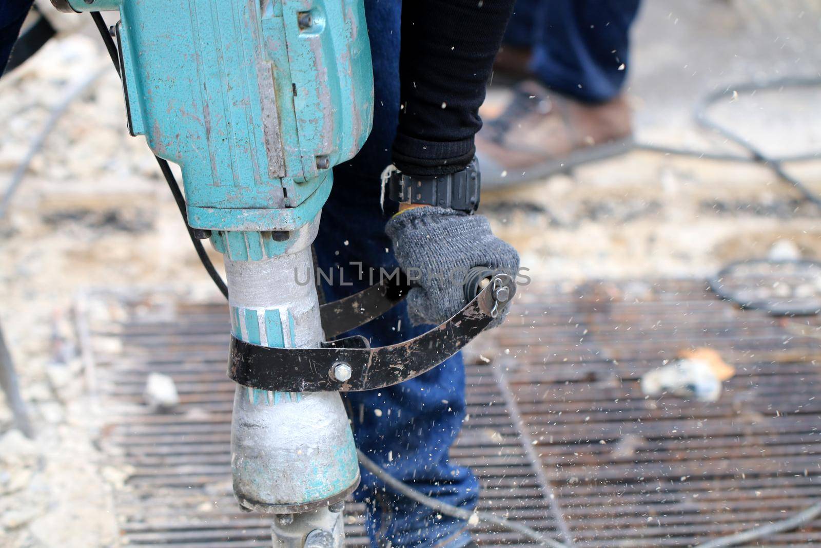 Male workers use electric concrete breaker for digging and drilling concrete repairing driveway surface with jackhammer at the local city road, during sidewalk, work construction site.