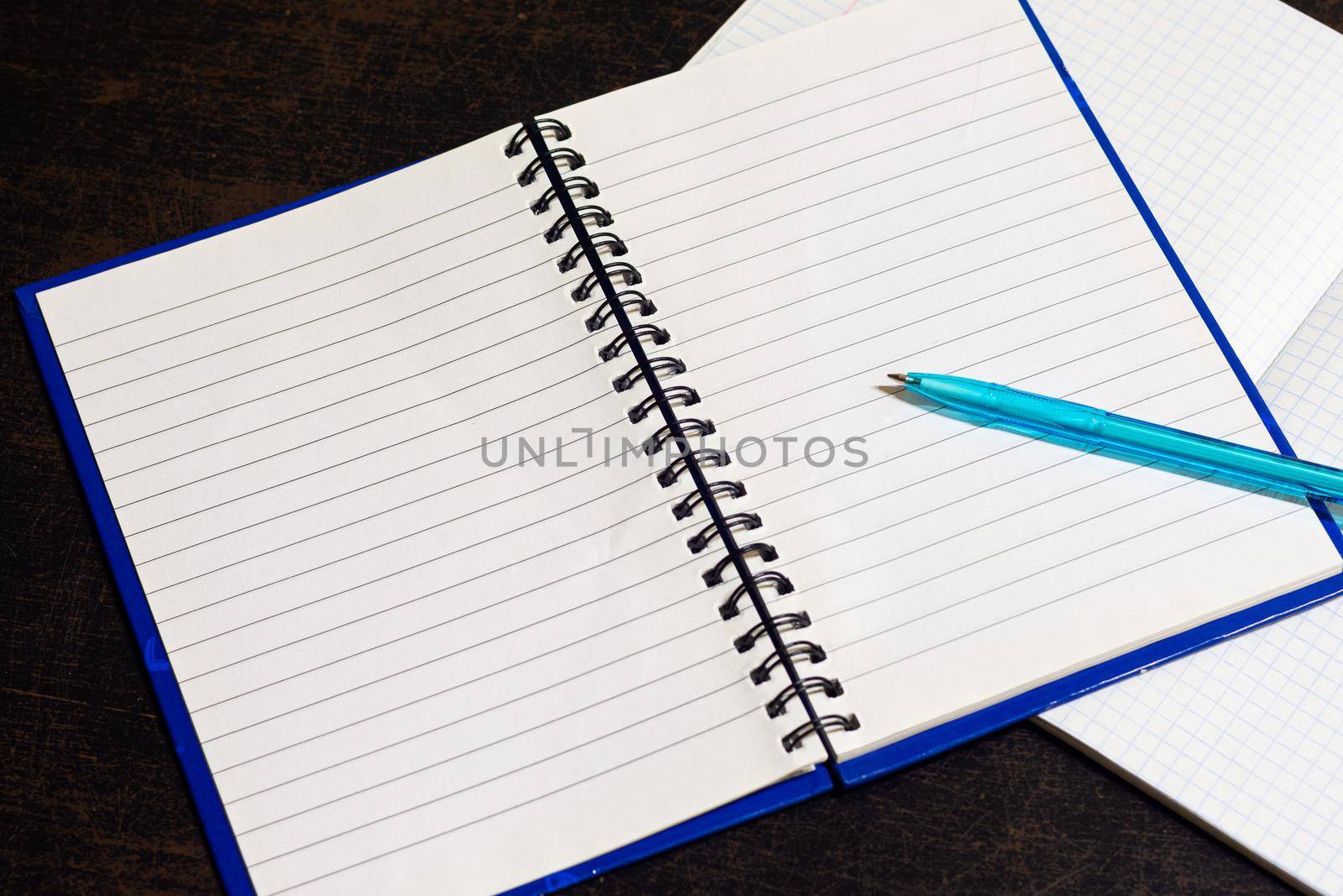 On the table is an open notebook on which lies a ballpoint pen