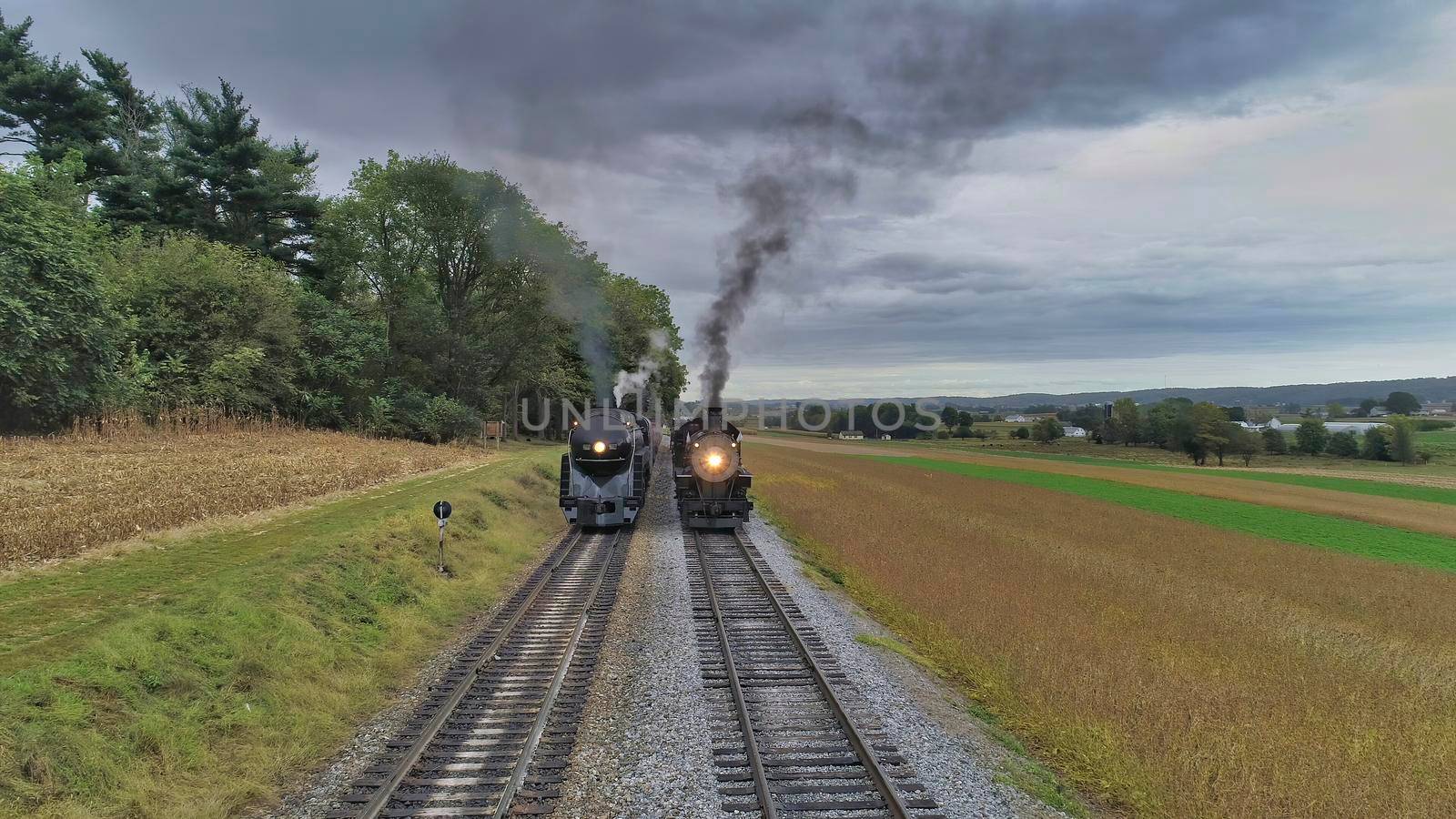 Aerial View of 2 Restored Antique Steam Engines and Passenger Cars Steaming Up at a Small Rail Road Station