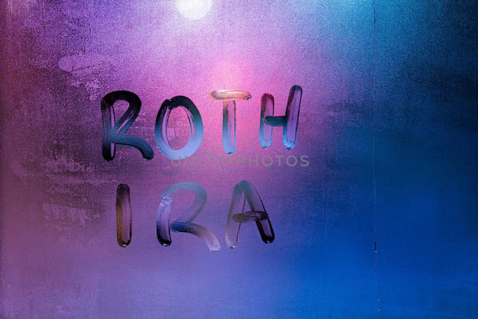 the words roth ira - individual retirement account - handwritten on night wet window glass surface. Idea was proposed by Senator William Roth.
