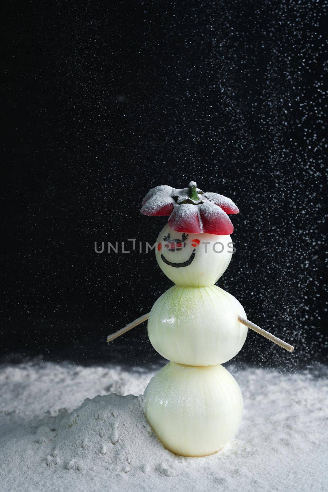 A snowman made of pearl onions stands on a snow. by sashokddt