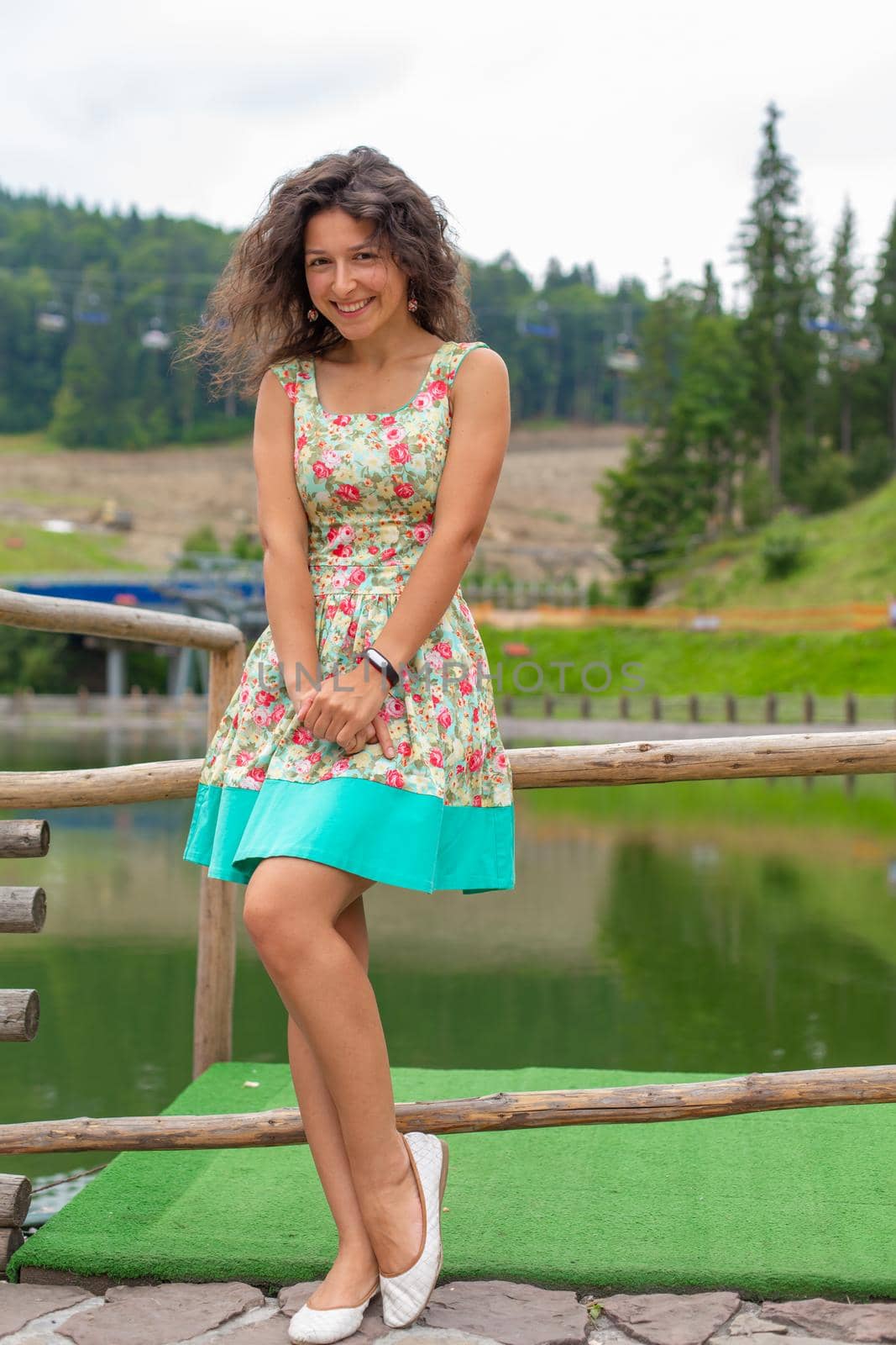 A beautiful slim girl posing in green summer park next to pond.