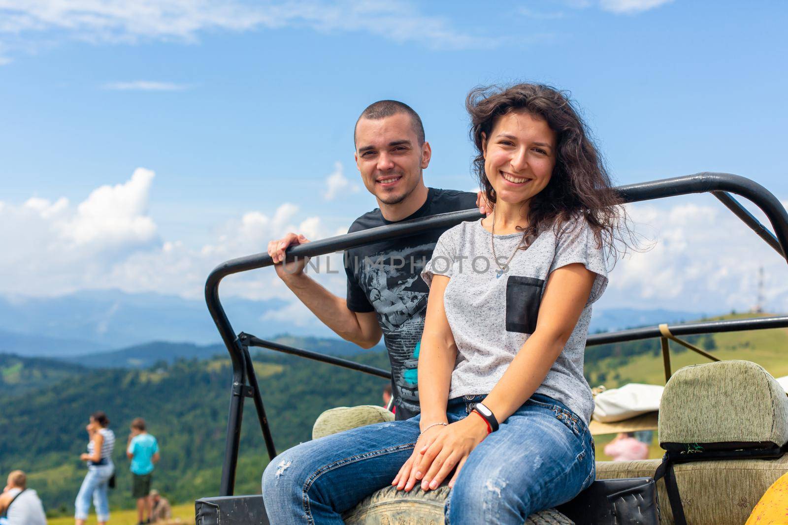 Happy young couple resting on the dirty offroad car. Highland car tour.