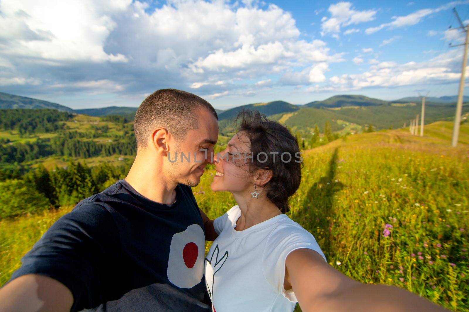 Young couple hugs and take selfie with amazing mountain landscape background by Try_my_best