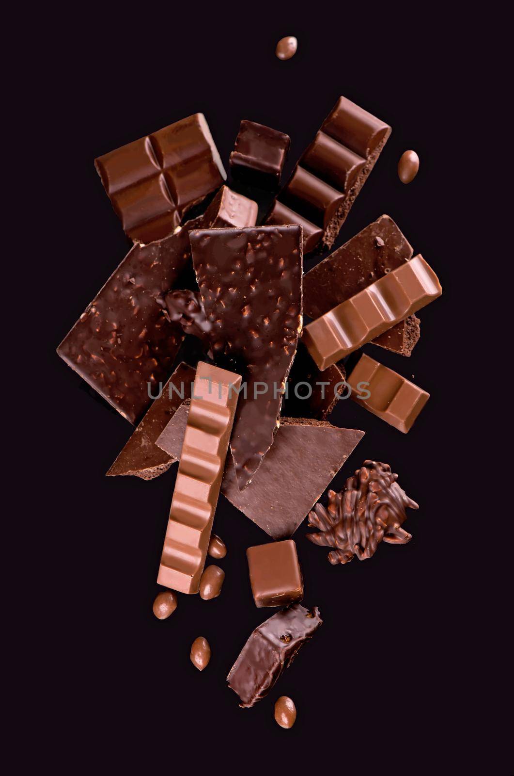 Broken chocolate pieces and cocoa powder on wooden background