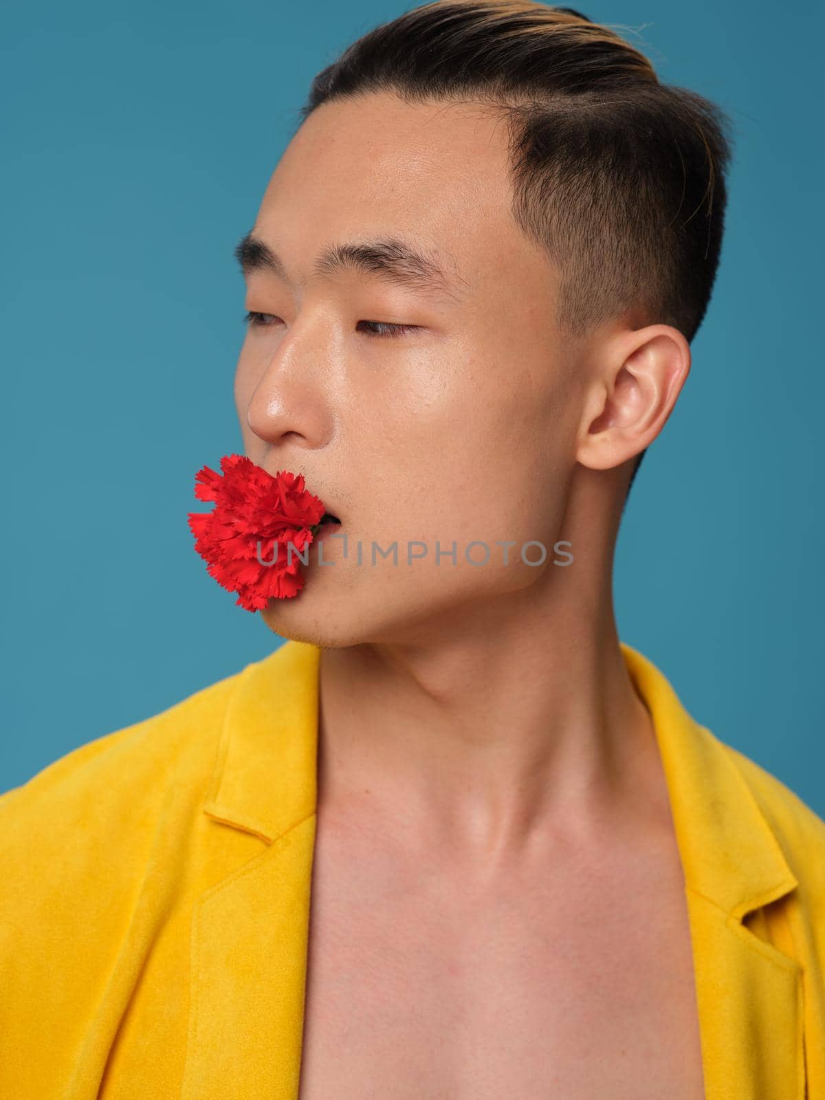 Korean appearance guy with a flower in his mouth on a blue background and a yellow jacket side view portrait by SHOTPRIME