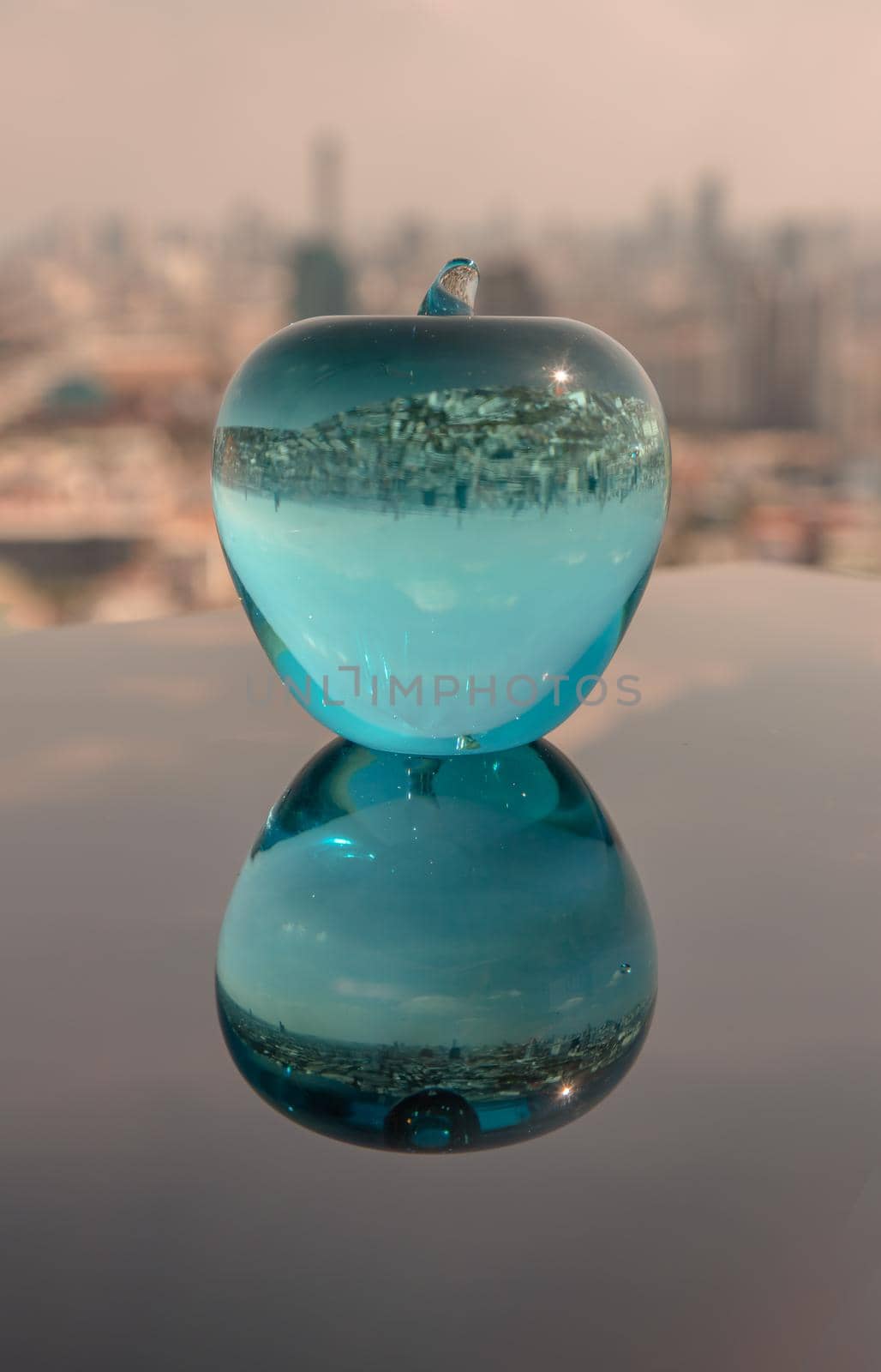Glass or Crystal blue apple and reflective surface on sky background. Copy space, Selective focus.