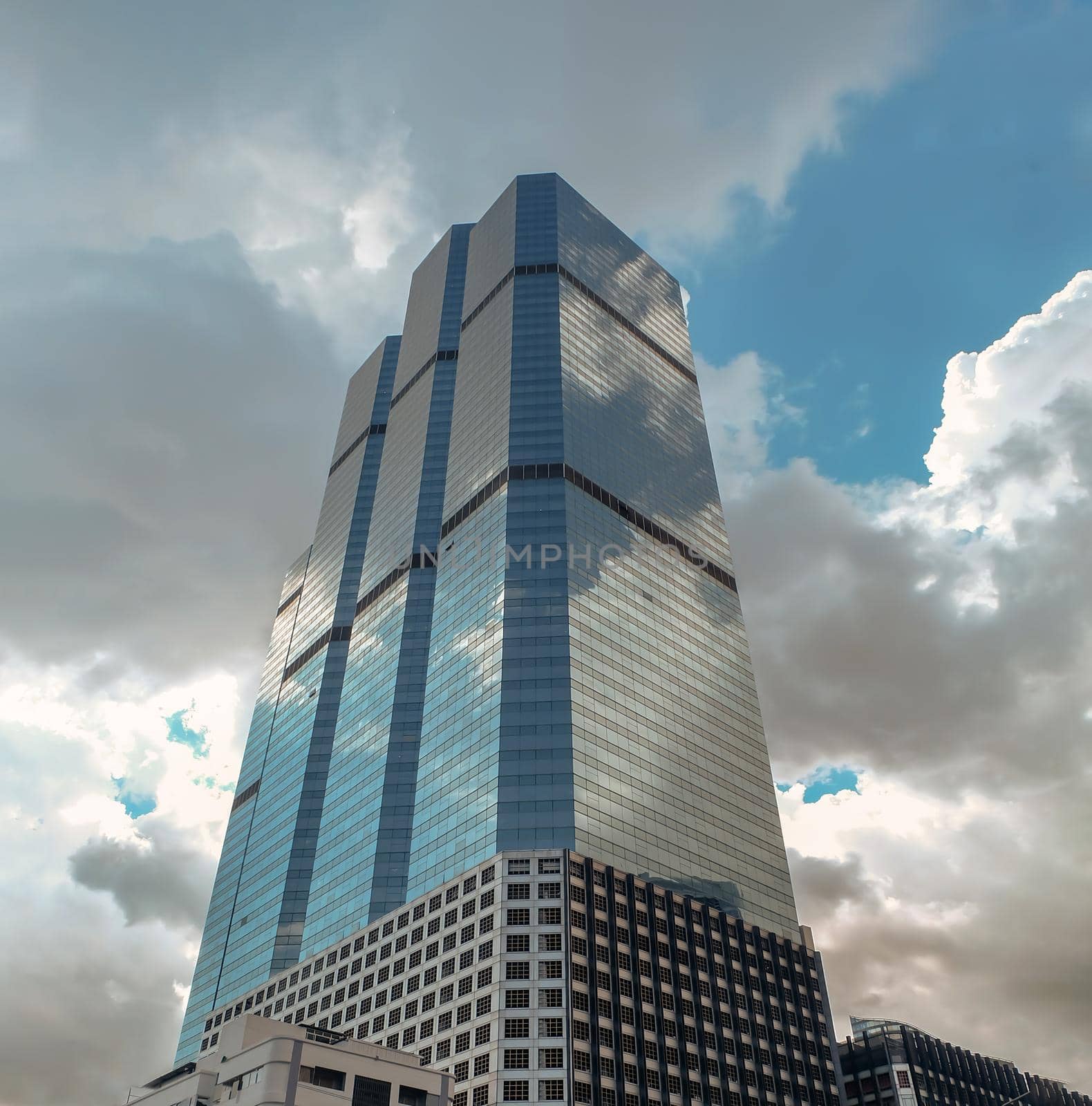 Bangkok, Thailand - July 10, 2019 :  Angular geometric mirror cladding on a modern building with repeating structure and reflected sky and clouds. No focus, specifically.