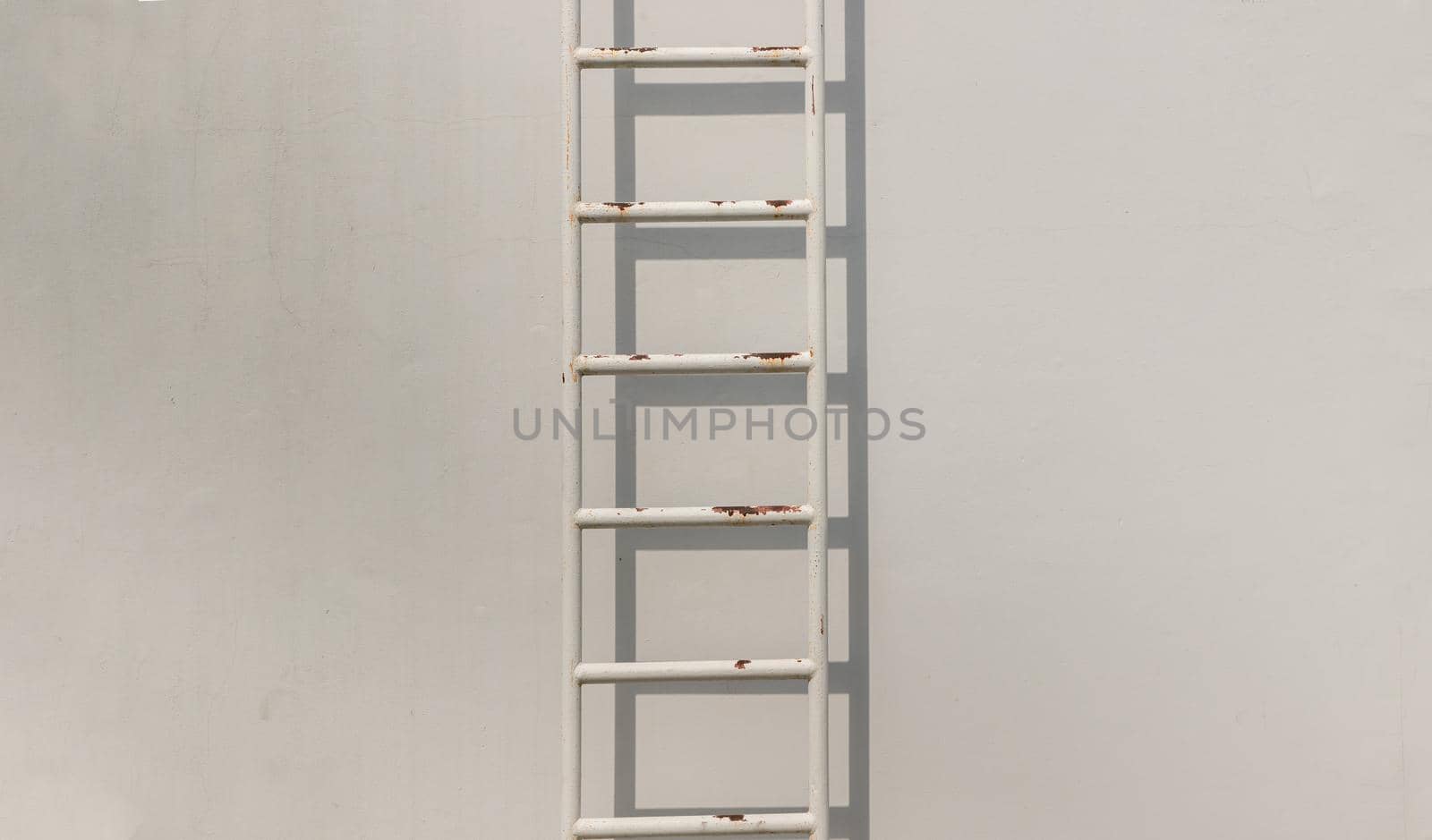 White metal fire escape attached to a wall and leading to the roof of a building. Copy space, Selective focus.