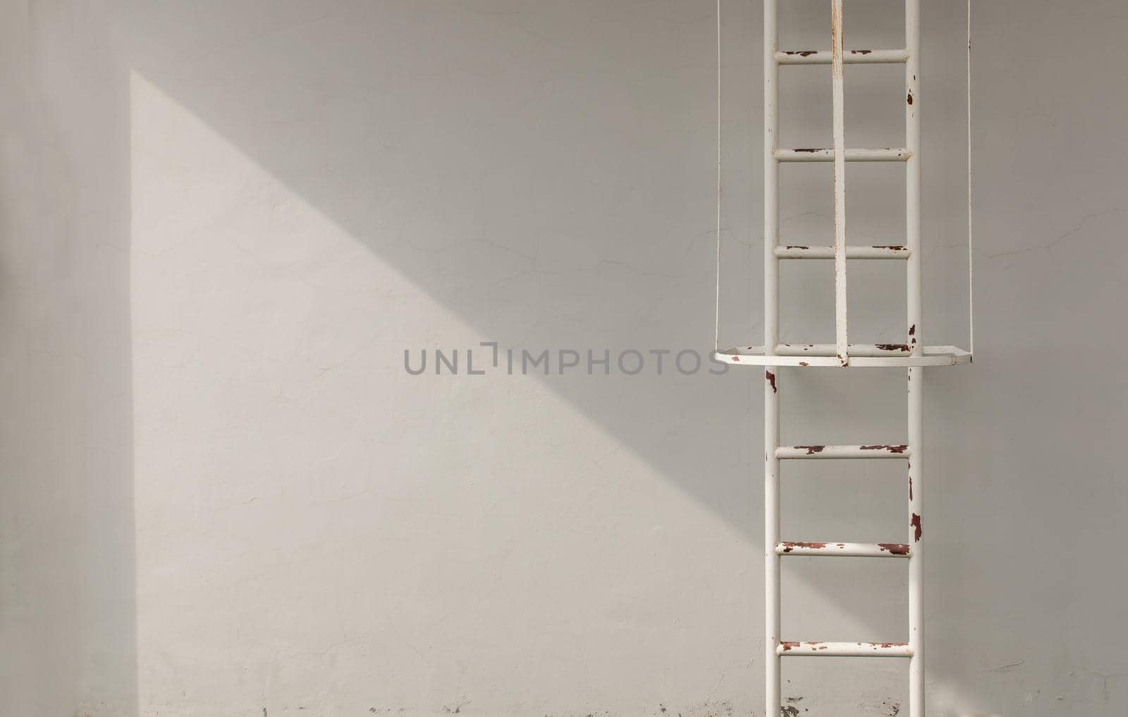 White metal fire escape attached to a wall and leading to the roof of a building. Copy space, Selective focus.