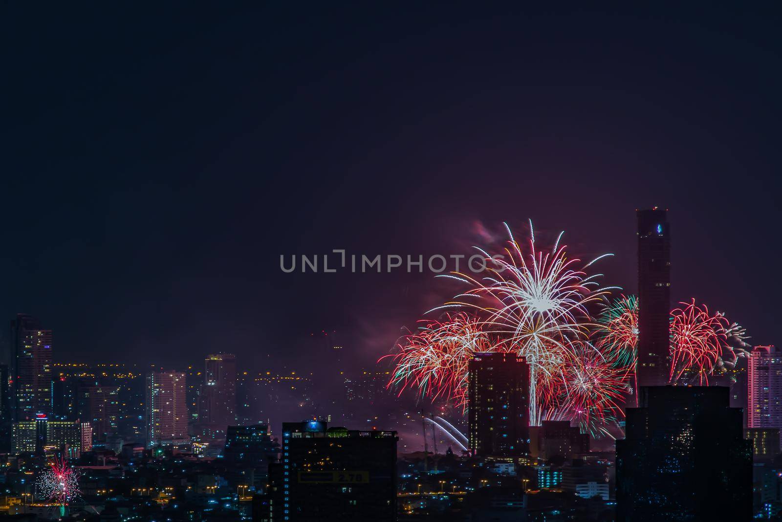 Colorful Firework with cityscape night light view of Bangkok skyline at twilight time. New Year celebration fireworks, Bangkok city,Thailand Fireworks light up to sky at Christmas & New Year festival with free space for text. No focus, specifically.