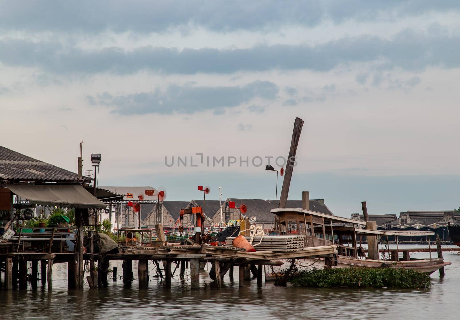Bangkok, Thailand - 04 Jan 2021 : Small Ferry Boat parked in front of the old riverfront wooden house at Chao Phraya river. Selective focus.