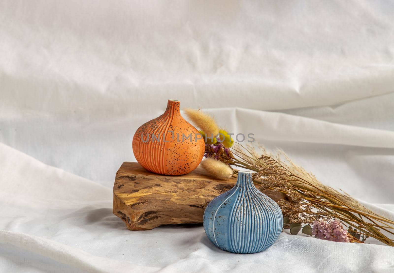 Two beautiful small ceramic vases with wooden logs and Dried flowers on White background. Ceramic tableware, Home decor.