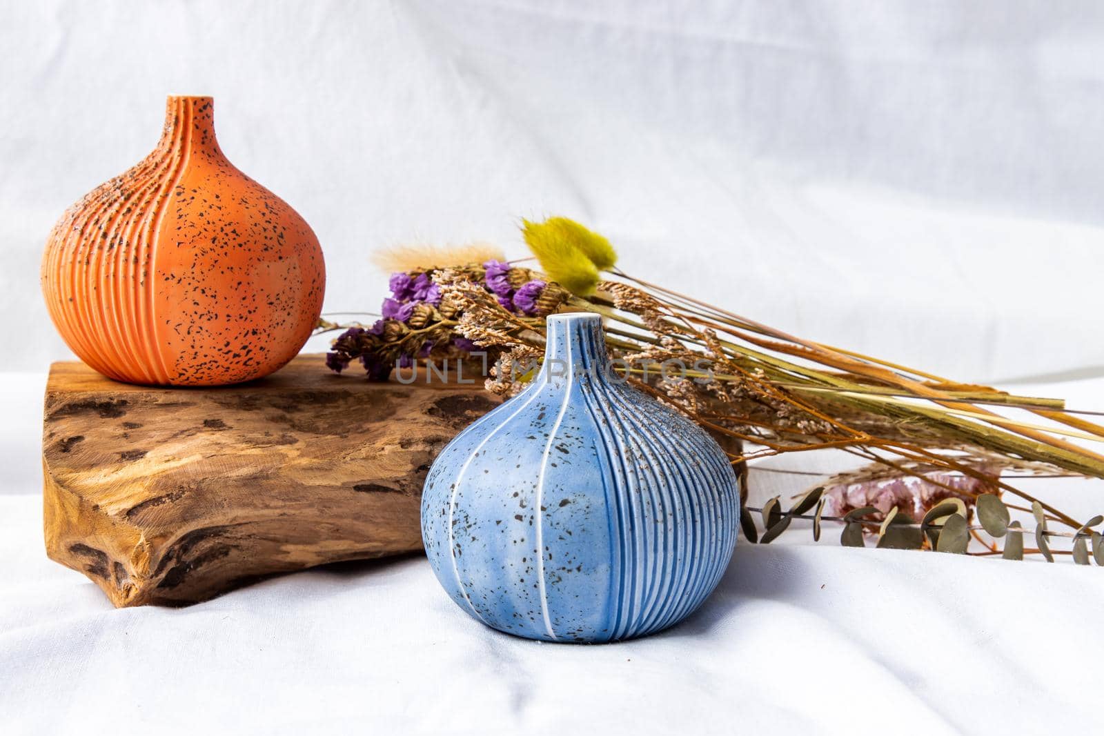 Two beautiful small ceramic vases with wooden logs on white background. Ceramic tableware, Home decor.