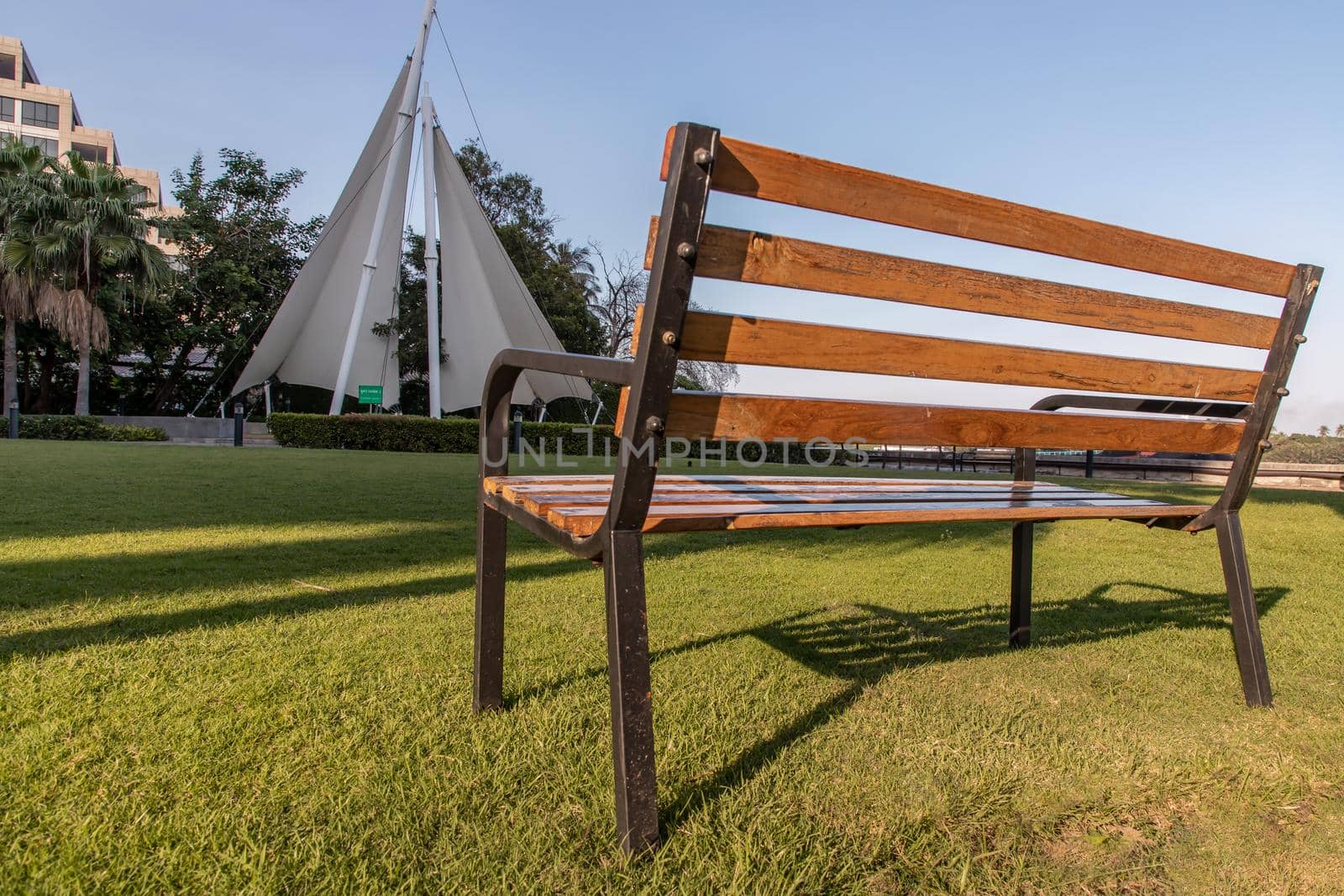 Wooden benches on grass floor in a shady area of the park at Condominium. Seating and unwind area. Selective focus.