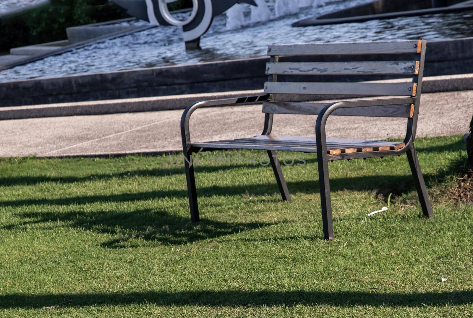 Wooden benches on grass floor in a shady area of the park. Seating and unwind area. Selective focus.