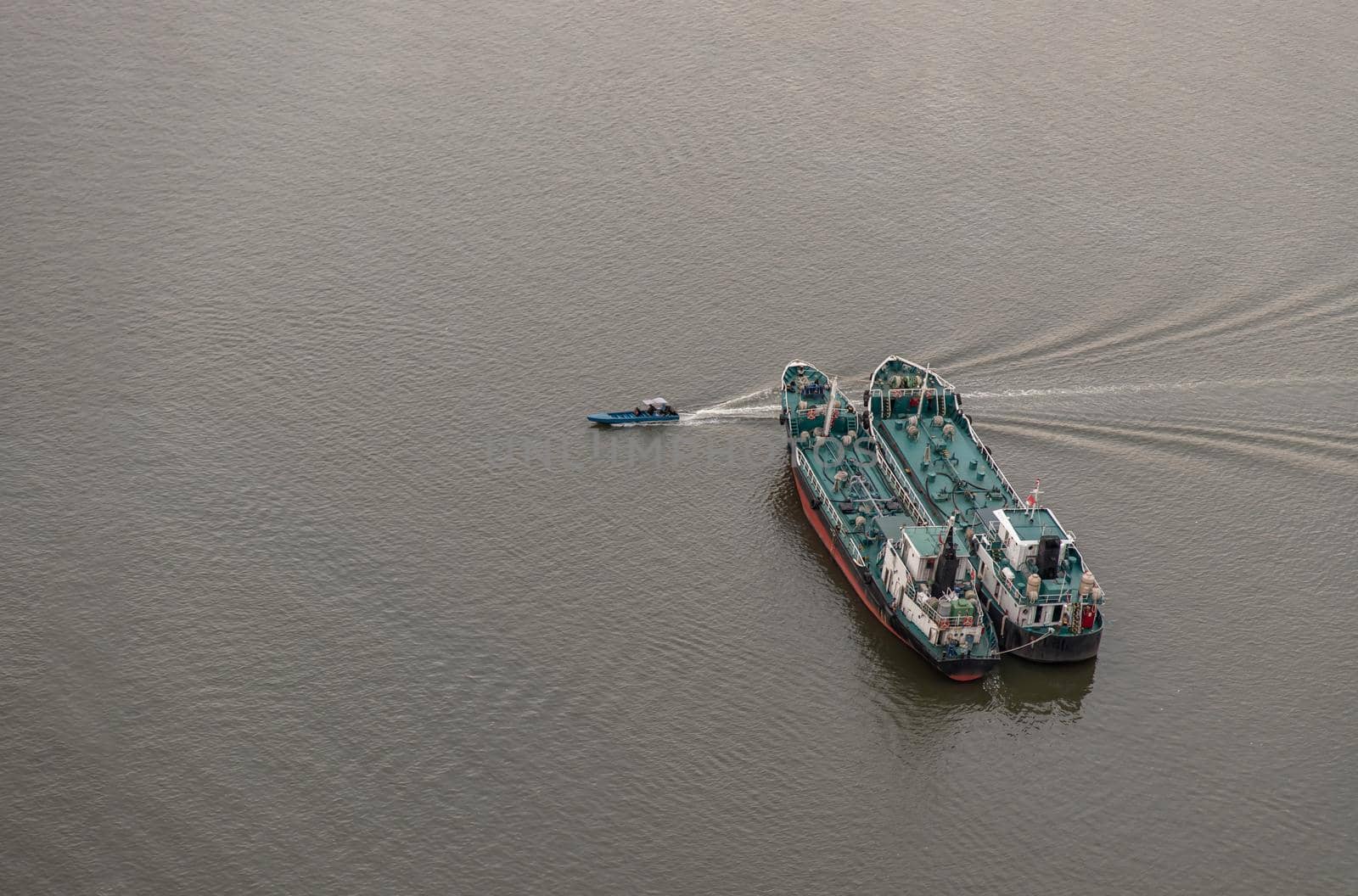 Bangkok, Thailand - 04 Jan 2021 : Aerial view of Two Cargo Ship and Small Ferry Boat in the Chao Phraya River at evening. Selective focus.